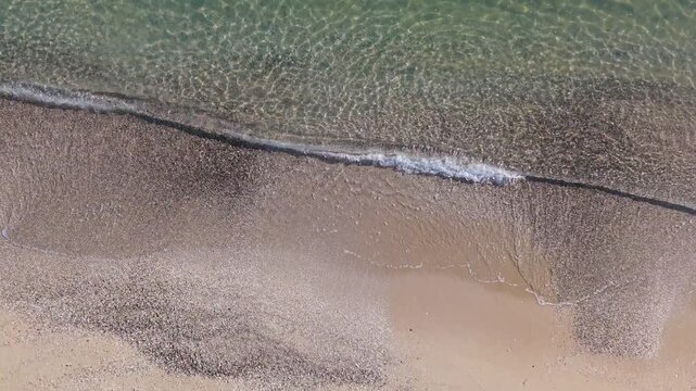 Foamy sea surf spreading across sandy shore with gentle movement and relaxing seaside atmosphere.