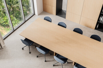 Fototapeta premium Top view of modern conference room with wooden table and office chairs near large window in tropical background setting. 3D Rendering