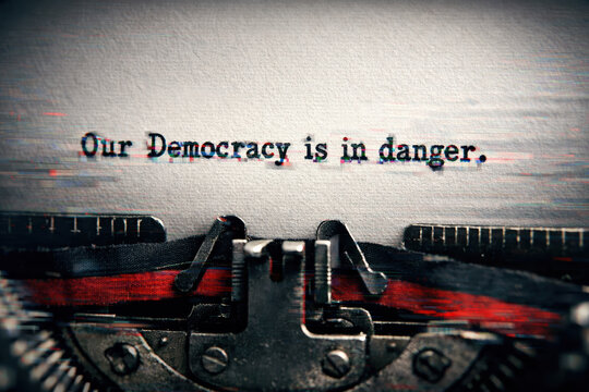 Distorted text on a typewriter warns of political crisis and civil unrest as democracy is in danger.