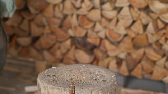 Hands placing a log on a chopping block and splitting it with an axe for firewood preparation