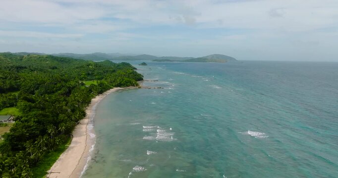 Turquoise sea water and waves. Coastline with trees and white sandy beach. Santa Fe, Tablas, Romblon. Philippines.