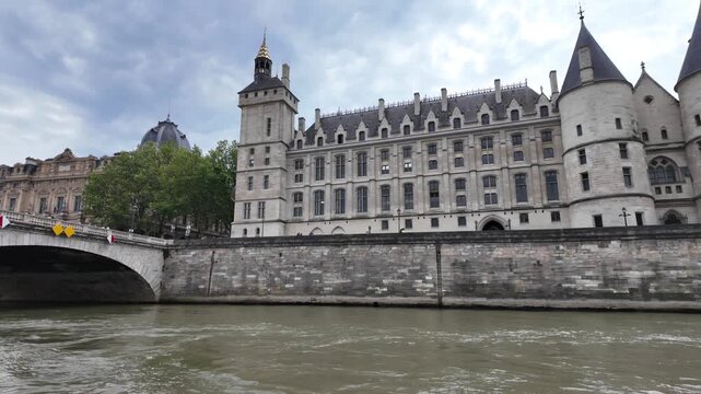 Navigating the seine river in paris showing the pont au change and the historic conciergerie, a former royal palace and prison on the &icirc;le de la cit&eacute; on a cloudy day