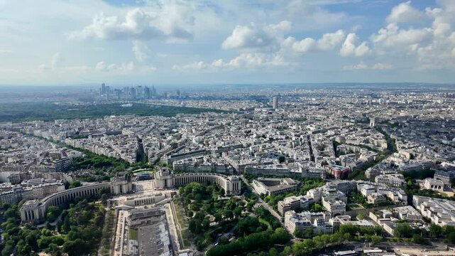 Expansive paris aerial view featuring the iconic trocad&eacute;ro gardens, the seine river, and the distant la d&eacute;fense business district skyline under a cloudy blue sky