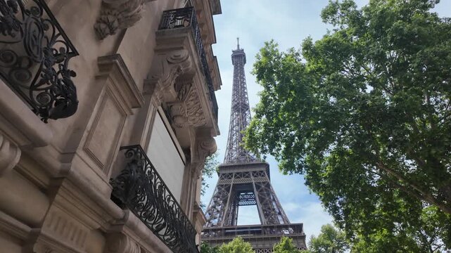 Eiffel tower rising between traditional parisian buildings. Showcasing european city architecture and classic parisian streetscape with landmark structure against a blue sky