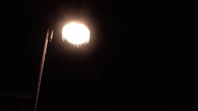 Winterzauber: Schneeflocken im atmosph&auml;rischem Licht einer Stra&szlig;enlaterne in der kalten Jahreszeit, Schneefall, Winternacht, Lampe
