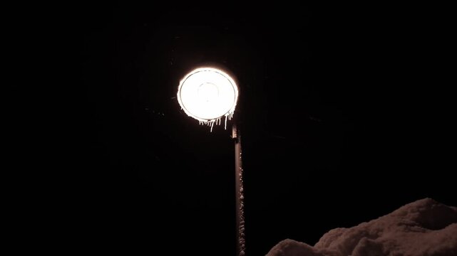Winterzauber: Schneeflocken im atmosph&auml;rischem Licht einer Stra&szlig;enlaterne in der kalten Jahreszeit, Schneefall, Winternacht, Lampe
