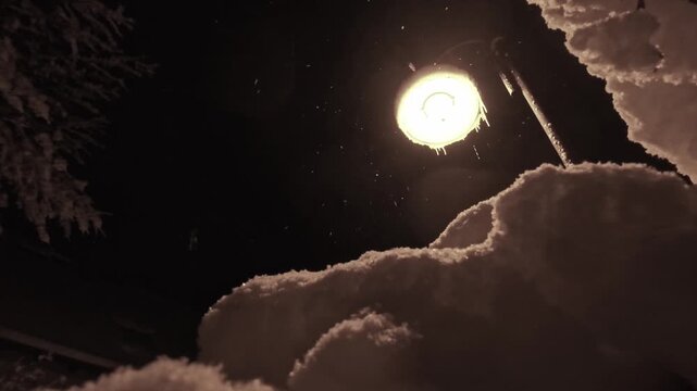 Winterzauber: Schneeflocken im atmosph&auml;rischem Licht einer Stra&szlig;enlaterne in der kalten Jahreszeit, Schneefall, Winternacht, Lampe
