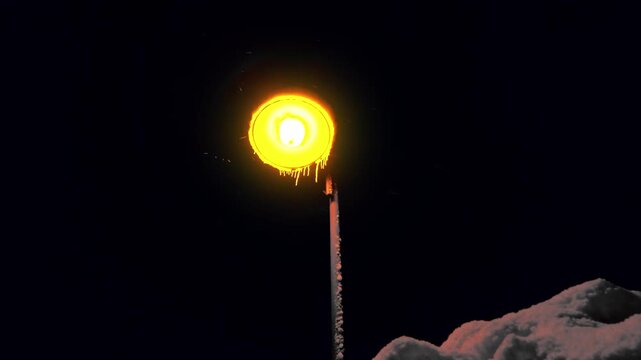 Winterzauber: Schneeflocken im atmosph&auml;rischem Licht einer Stra&szlig;enlaterne in der kalten Jahreszeit, Schneefall, Winternacht, Lampe

