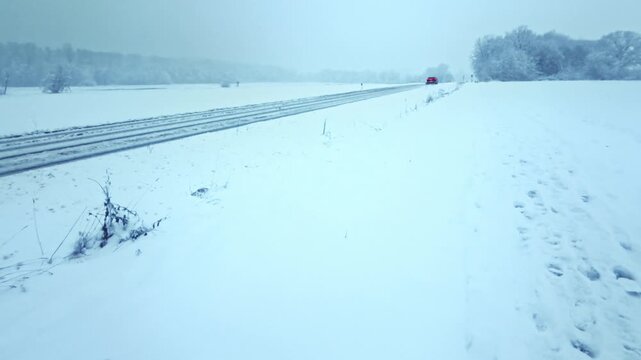 winterliche verschneite Landstra&szlig;e: Auto, Stra&szlig;enverkehr, Glatteis, Schneematsch und eisige Bedingungen, Wintersdienst, Sicherheit, Unfallgefahr, Transport, Landschaft

