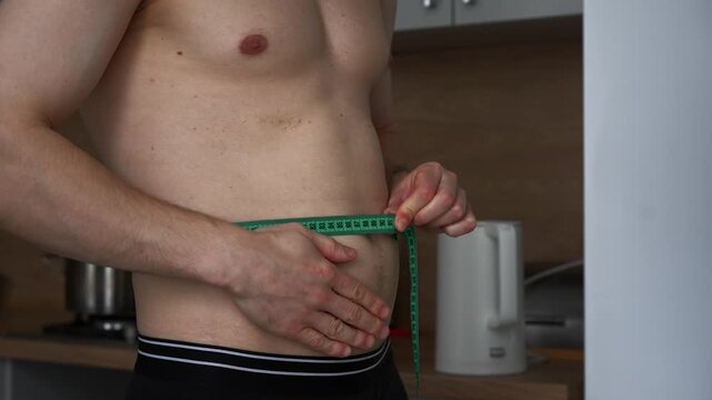 Excess weight.
The problem of obesity.
A man measures his waist with a measuring tape.
A man on a diet.
A man with a big belly.