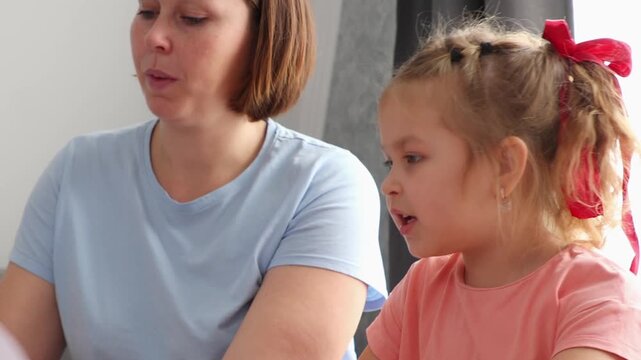 Close up of Caucasian mother and daughter reading a book together. Pre-school children's education.