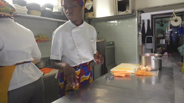 African woman chef preparing fresh ingredients for traditional cuisine in a professional kitchen