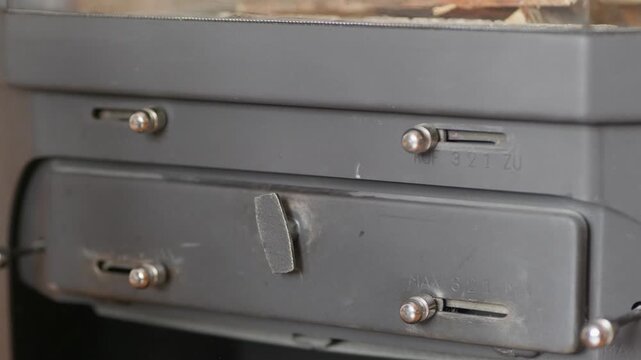 Close up of male hands opening air intake metal levers on wood burning fireplace to control the fire intensity