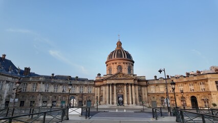 Institut de france building on the left bank in paris, france, showcasing 17th-century classical architecture, its historic dome under a clear blue sky during a quiet afternoon