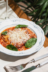Classic lasagna served with rich tomato sauce grated cheese and fresh basil presented on ceramic plate with dramatic side light and deep shadows