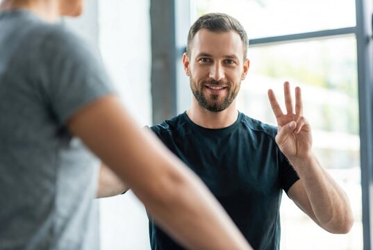 Smiling fitness coach or client showing three fingers, counting reps or sets during a workout in a gym.