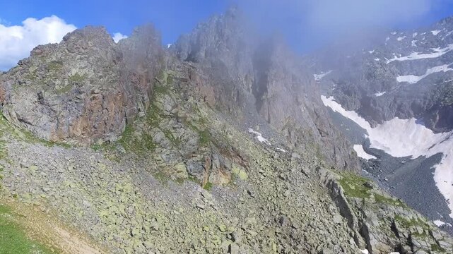 Aerial timelapse of sharp rocky alpine mountain peaks in summer across high altitude USA ranges. Rugged cliffs and exposed ridgelines reveal dramatic geology under clear blue sky.