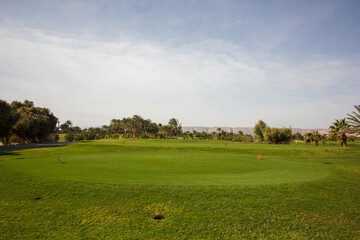 A golf course with a green grassy field and a small hole