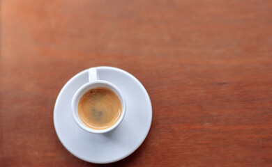 Obraz premium Espresso coffee cup on white saucer placed on wooden table surface