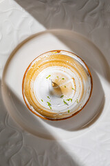 Lemon tart topped with toasted meringue and citrus zest served on elegant white plate