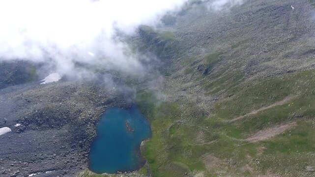 Aerial view of high altitude mountain tarn lakes within the Rocky Mountains wilderness summer light. Clear water and rugged alpine terrain reveal pristine glacial basins and remote peaks.