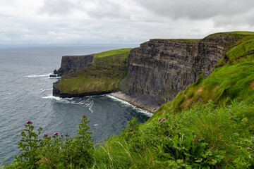 a rainy and stormy summer day at the famous cliffs of moher in the irish County Clare. With a view down to a small beach