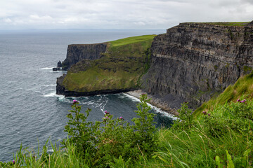 a rainy and stormy summer day at the famous cliffs of moher in the irish County Clare. With a view down to a small beach