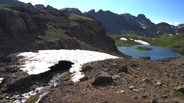 The stream formed by the melting snow waters on the mountain flows through the ice tunnel as it flows towards the alpine lake