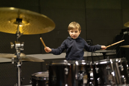 Young boy learning playing drums in music studio