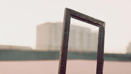 An empty frame stands on a rooftop, capturing the essence of creativity. Behind it, buildings loom softly in the fading light, creating a peaceful twilight atmosphere. © icetray