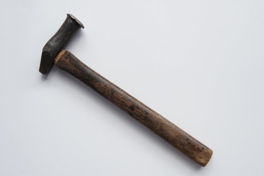 old hammer isolated on white. a top-down view of an old, rustic hammer featuring a dark wooden handle and a weathered metal head. the tool is positioned diagonally against a clean, plain white backgro