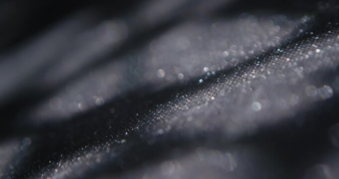 Closeup of abstract light spots projected onto dark textured surface, creating a high contrast organic pattern for modern backgrounds. Slow motion.
