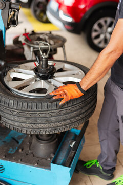 Mechanic in auto repair shop mounting tire on rim with tire changer