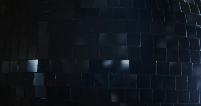 Detailed view of shiny mirror tiles on a disco ball, capturing light reflections and textures. Slow motion.