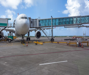 Avion à réaction long-courrier sur le tarmac relié à sa passerelle d’accès à bord 