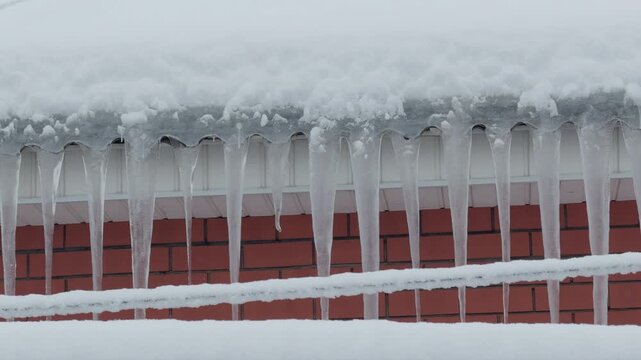 Icicles hanging from snowy roof on a cold winter day.
