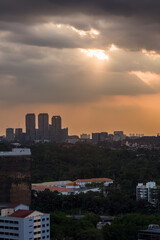 Obraz premium Golden sunlight breaking through storm clouds over buildings in Kuala Lumpur