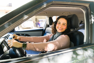 Woman driving car, looking at camera and smiling while commuting in city traffic, wearing smartwatch