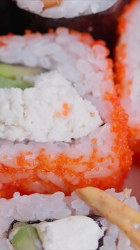 Close up sushi rolls with orange tobiko cream cheese filling white rice nori edges pickled ginger garnish bright natural light gourmet texture foodie instagrammable plating