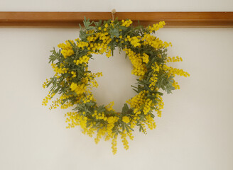 白い壁にかかったミモザのリース