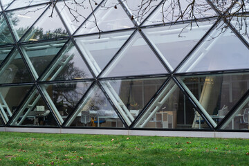 Naklejka premium Modern architecture featuring a geometric triangular glass facade and office interior