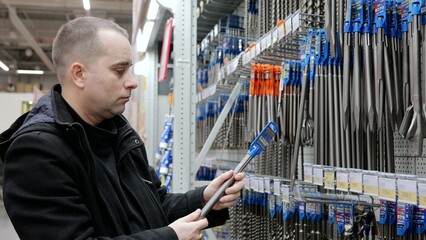 Fototapeta premium Construction worker examining drill bits at hardware store, comparing sizes and materials for professional renovation work