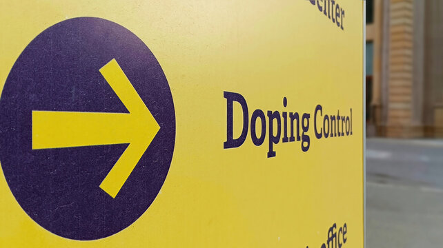 Shabby yellow arrow pointing to doping controls laboratory at sports facility on avenue (blurred photo)