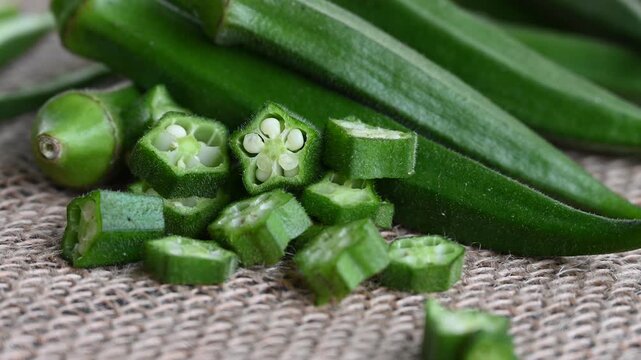 Farm fresh raw okra slices on wooden rustic aged chopping board. Close up of Lady Fingers or Okra over wooden background.