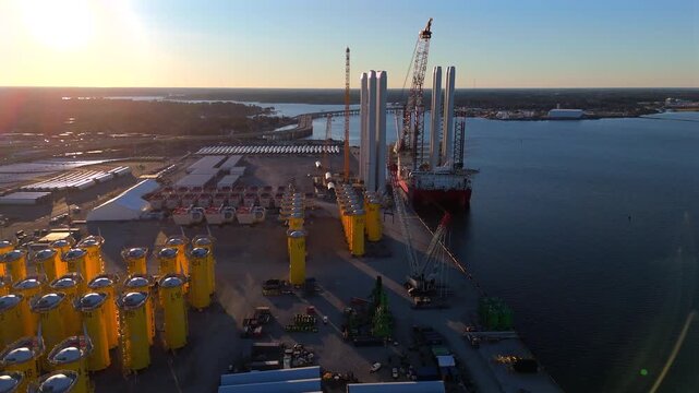 Aerial view of Norfolk wind terminal with jack-up vessel and turbine parts at golden hour
