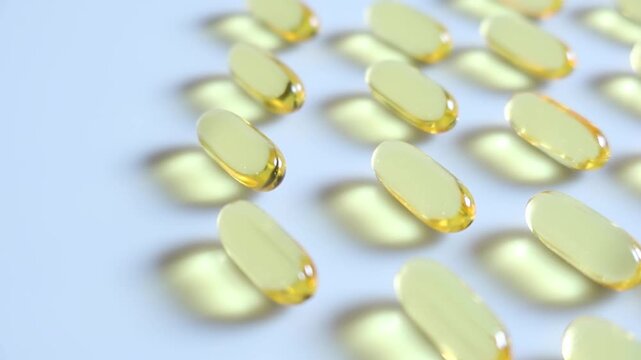 Close up Yellow fish oil capsules on the white floor. Slow motion video.