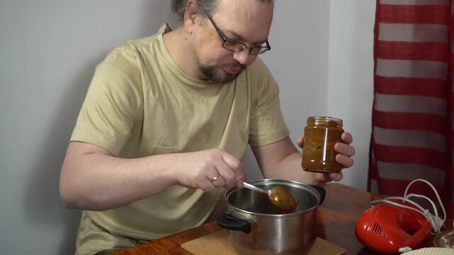 Cooking food at home. A man is holding a can of condensed milk and pouring the cream into a saucepan.