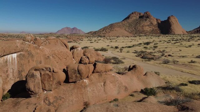 Spitzkoppe, or Spitzkop, is a unique pink granite rock formation in the landscape of Damaraland, Namibia, Africa. Aerial view.