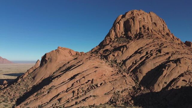 Spitzkoppe, or Spitzkop, is a unique pink granite rock formation in the landscape of Damaraland, Namibia, Africa. Aerial view.