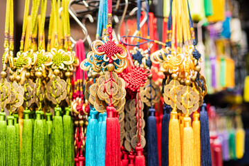 Fototapeta premium Tassels and charms are displayed on a rack at a market. They are made with different colors and materials. Shoppers can see the details in the sunlight during the day
